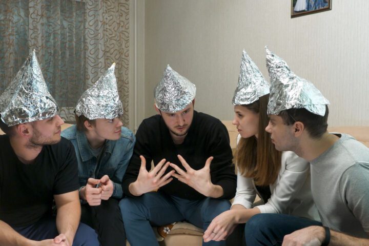 Group of people with foil on their heads discussing conspiracy theories. Friends with foil on their heads. You know, so they can't read your mind