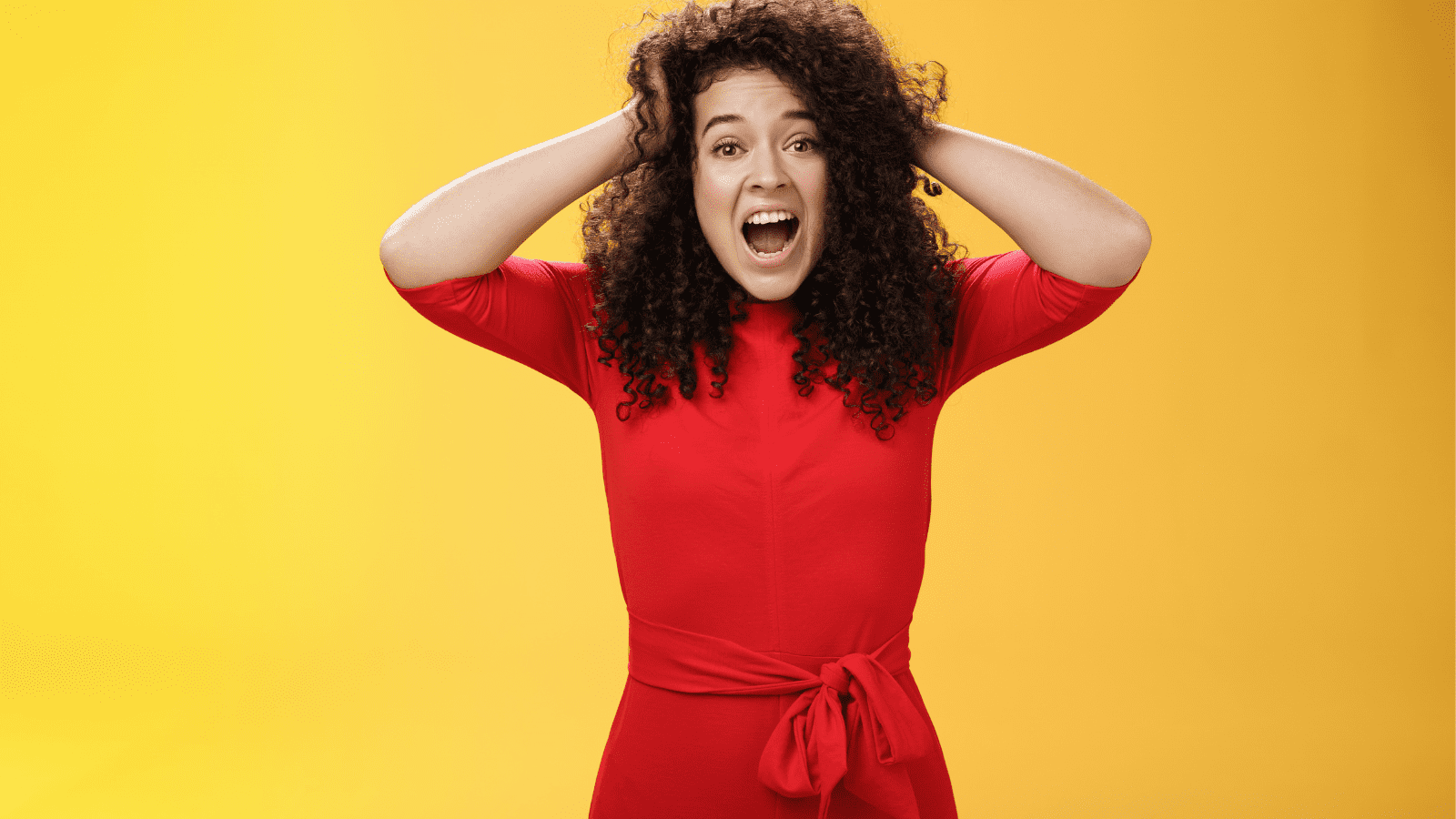 Girl Feeling Pressure Standing Anxious in Panic Holding Hands on Curly Hair Yelling at Camera Disturbed, Freaked Out Being Tensed and Upset with Bad Situation, Standing Troubled over Yellow Background