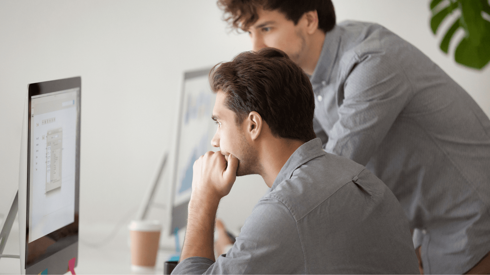 Caucasian male coach helping colleague with computer issues in office